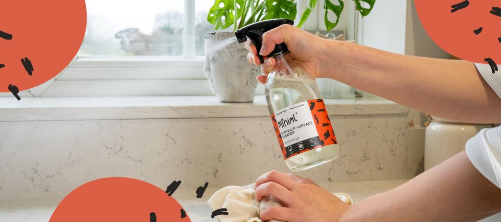 Homeowner cleaning fruit fly damage from kitchen wall using microfiber cloth and cleaning solution