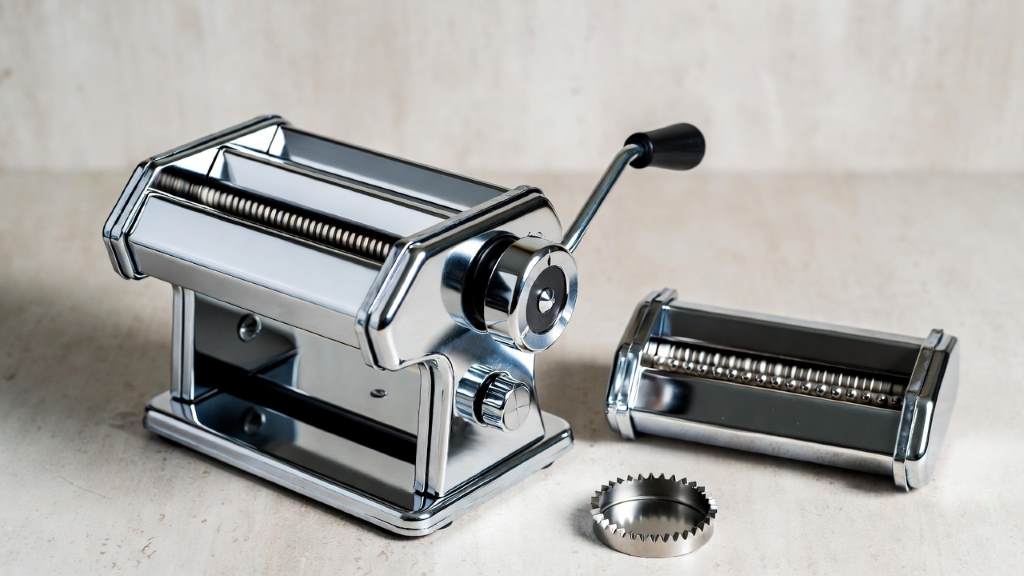 Stainless steel pasta machine with adjustable thickness dial and cutting attachments displayed